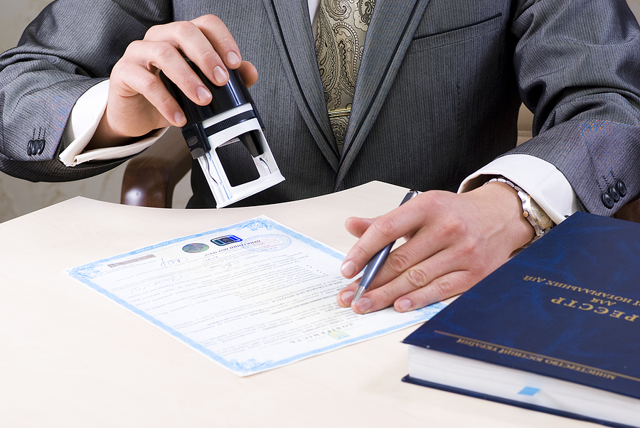 Man in a suit stamping a document for certification 