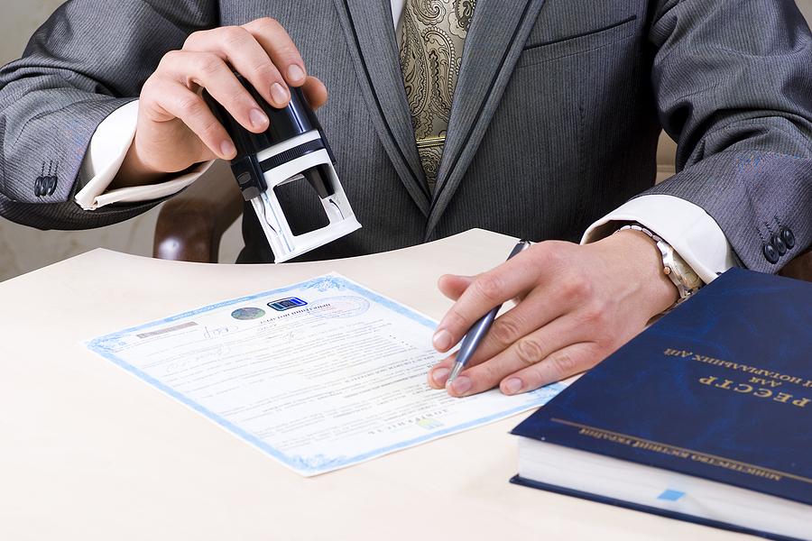 Man in a suit stamping a document certified